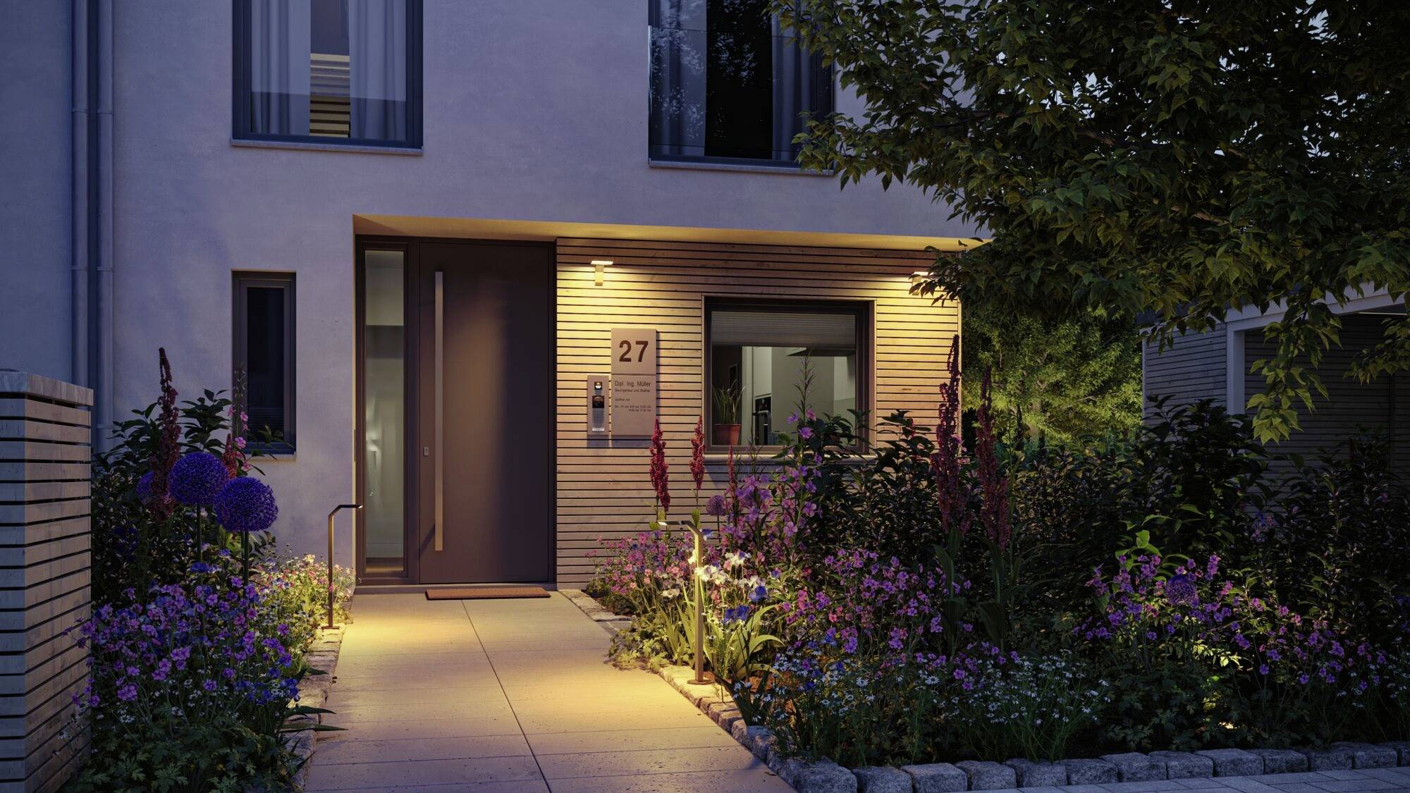 Moderní fasáda domu s osvětleným vchodem a udržovanou zahradou. Rostliny lemují cestu k hlavním dveřím. Číslo domu 27 je viditelné.