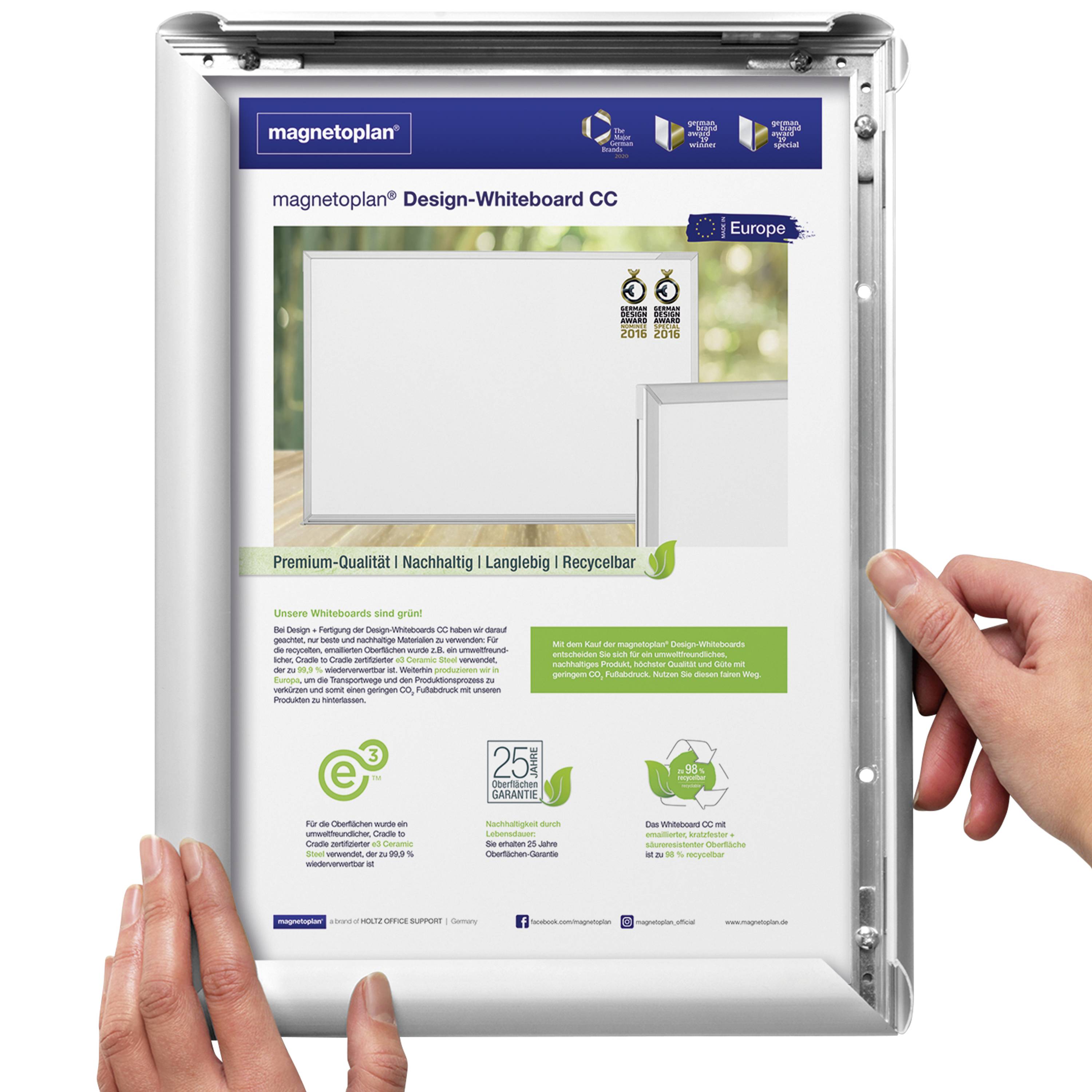 Kovový rám s plakátem 'magnetoplan Design-Whiteboard CC'. Charakteristiky: prémiová kvalita, udržitelný, recyklovatelný. Ruce otevírají rám.