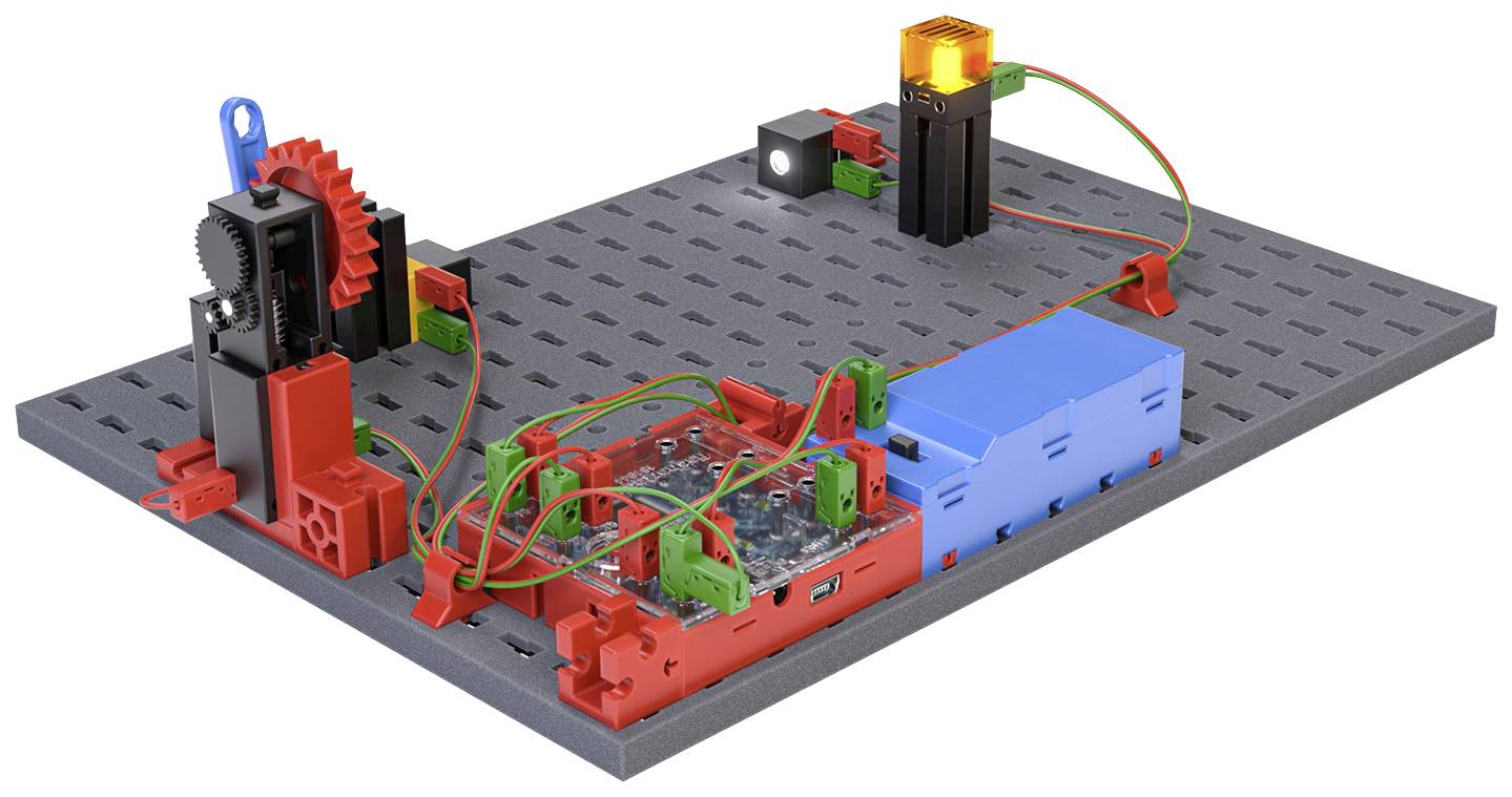 Dílna pro stavbu modelů s elektronickými komponenty, ozubenými koly a barevnými kabely na šedé základní desce.