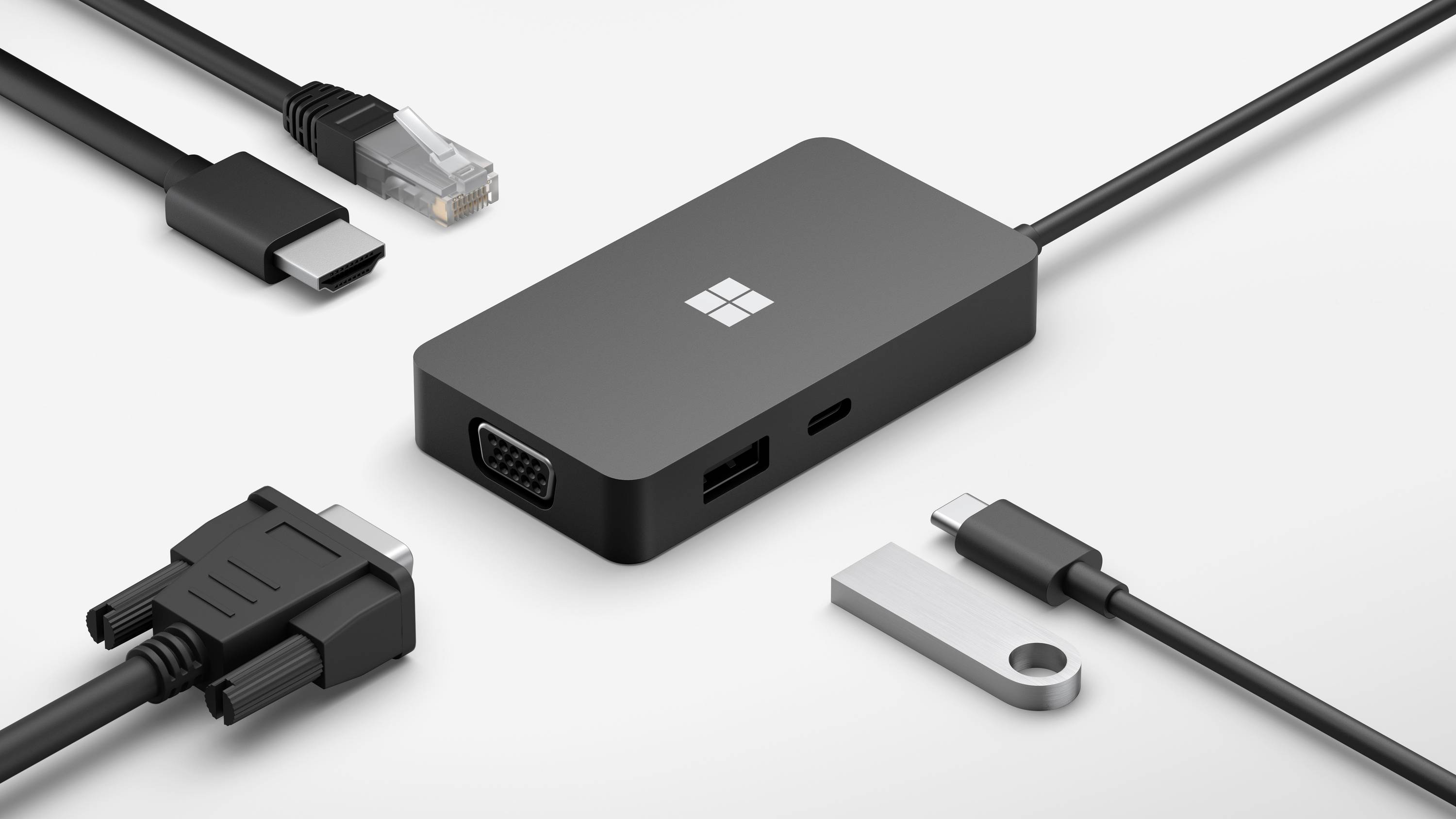 Černý adaptér s různými konektory: HDMI, VGA, USB-C, Ethernet a USB-A, obklopený příslušnými kabely.