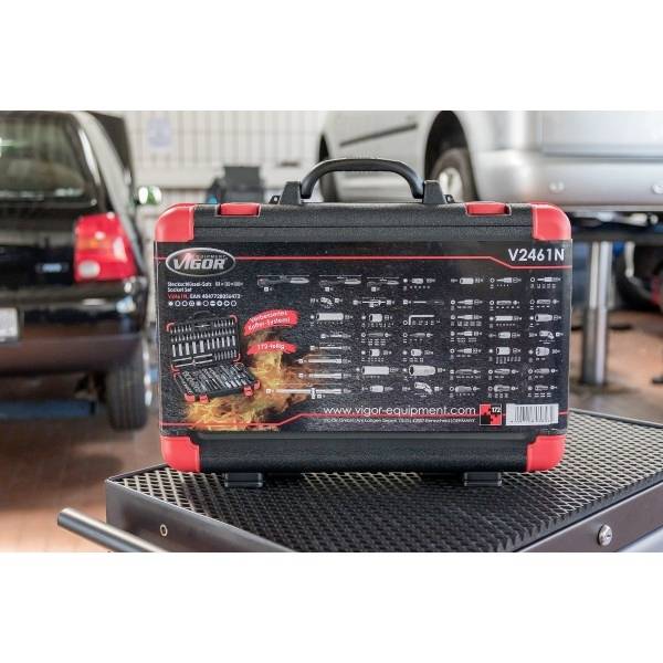 Černočervený montážní box značky 'Vigor V2461N' s vyobrazením různých nástrojů na jeho obalu, umístěný v garáži s auty v pozadí.
