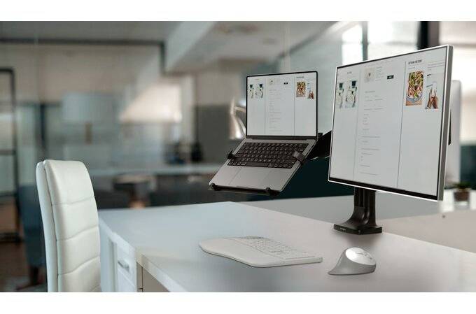 Moderní kancelář s psacím stolem, laptopem a monitorem. Místnost je světle osvětlená.