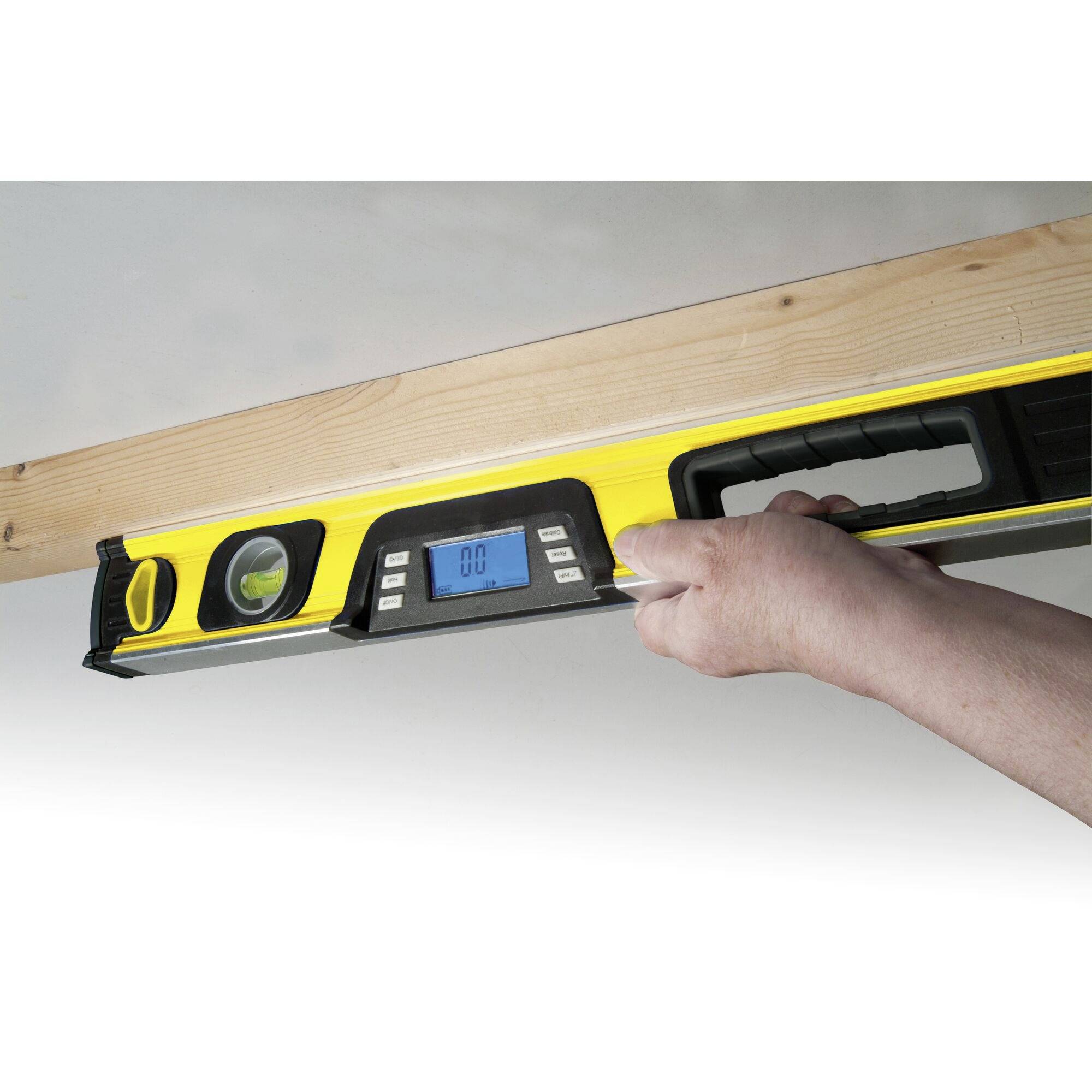 Jedna ruka drží žlutou vodováhu na dřevěné desce. Digitální displej ukazuje '0,0°', což signalizuje, že povrch je vyrovnaný.
