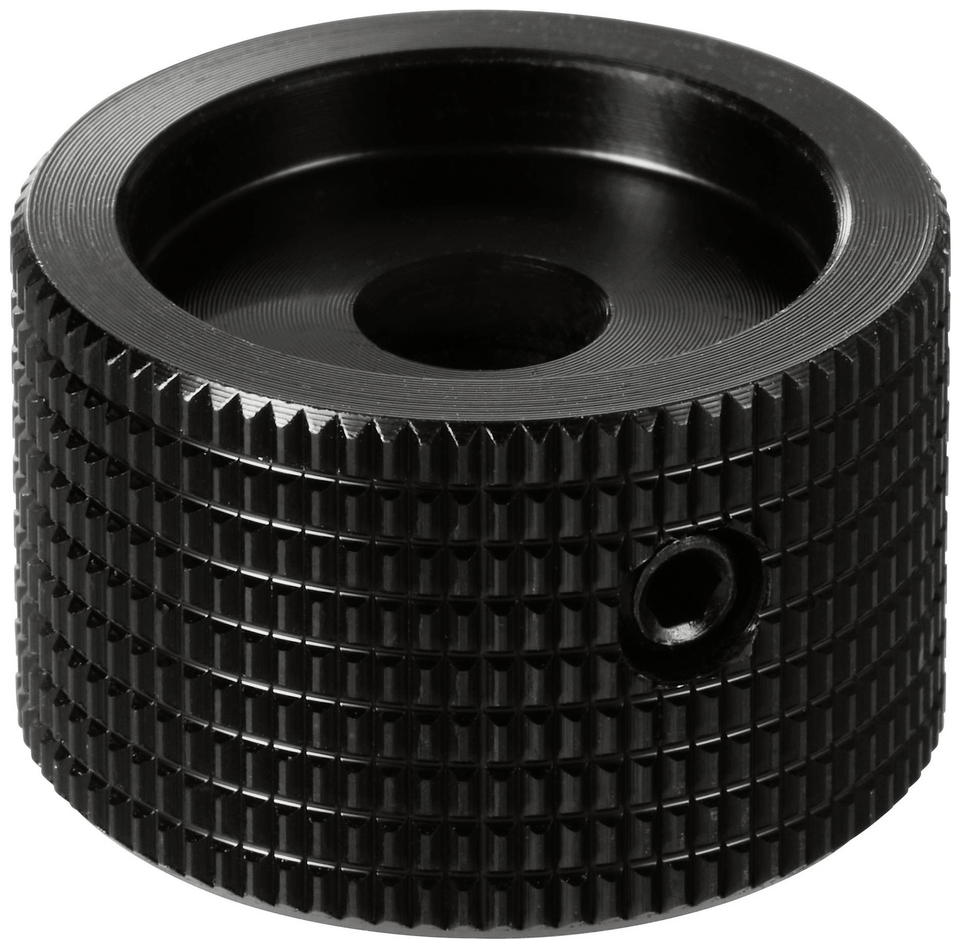 Černý vroubkovaný kovový knoflík s centrálním otvorem a postranním šroubem, pravděpodobně součást mechanického přístroje nebo nástroje.