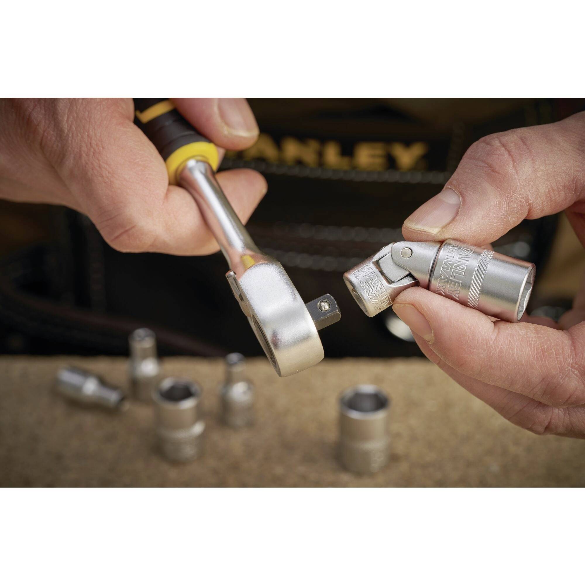 Jedna ruka drží nástrčný klíč, zatímco druhá ruka upevňuje adaptér. V pozadí leží další nástrčné klíče.