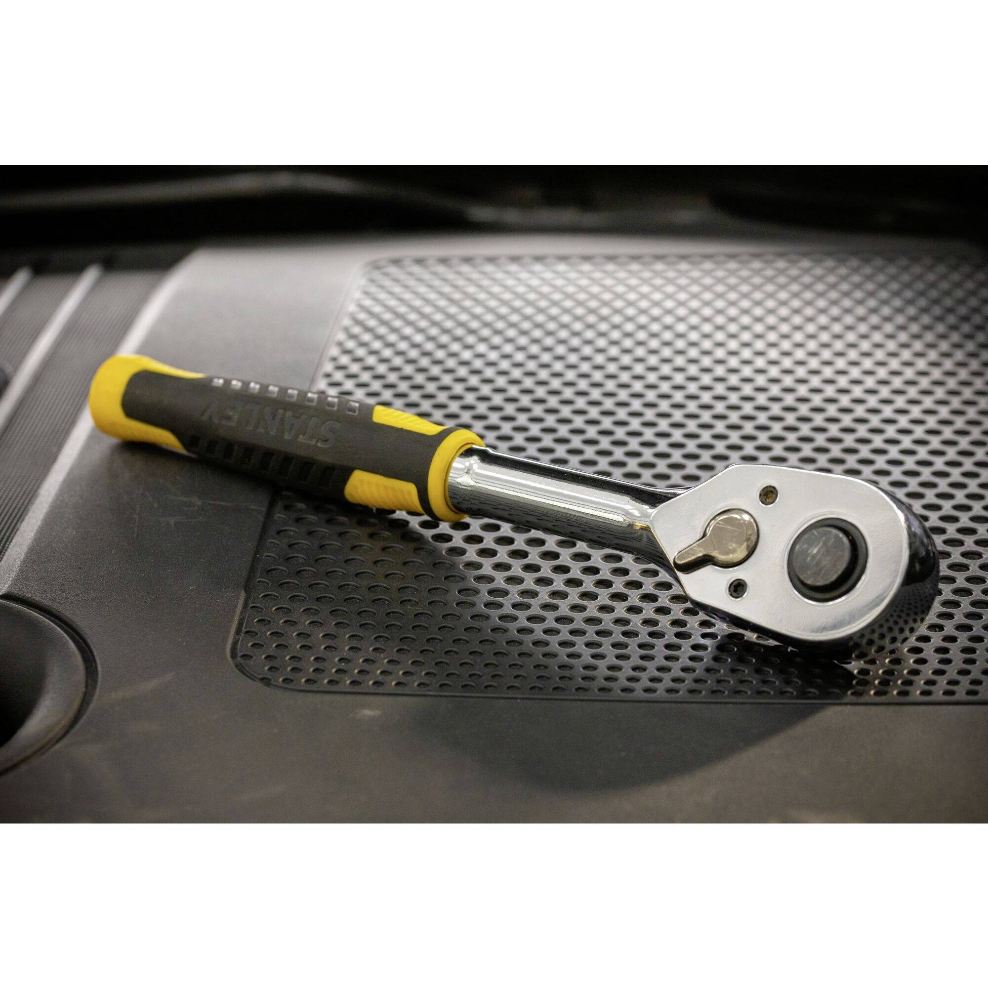 Francouzský klíč s černožlutou rukojetí ležící na tečkované ploše.