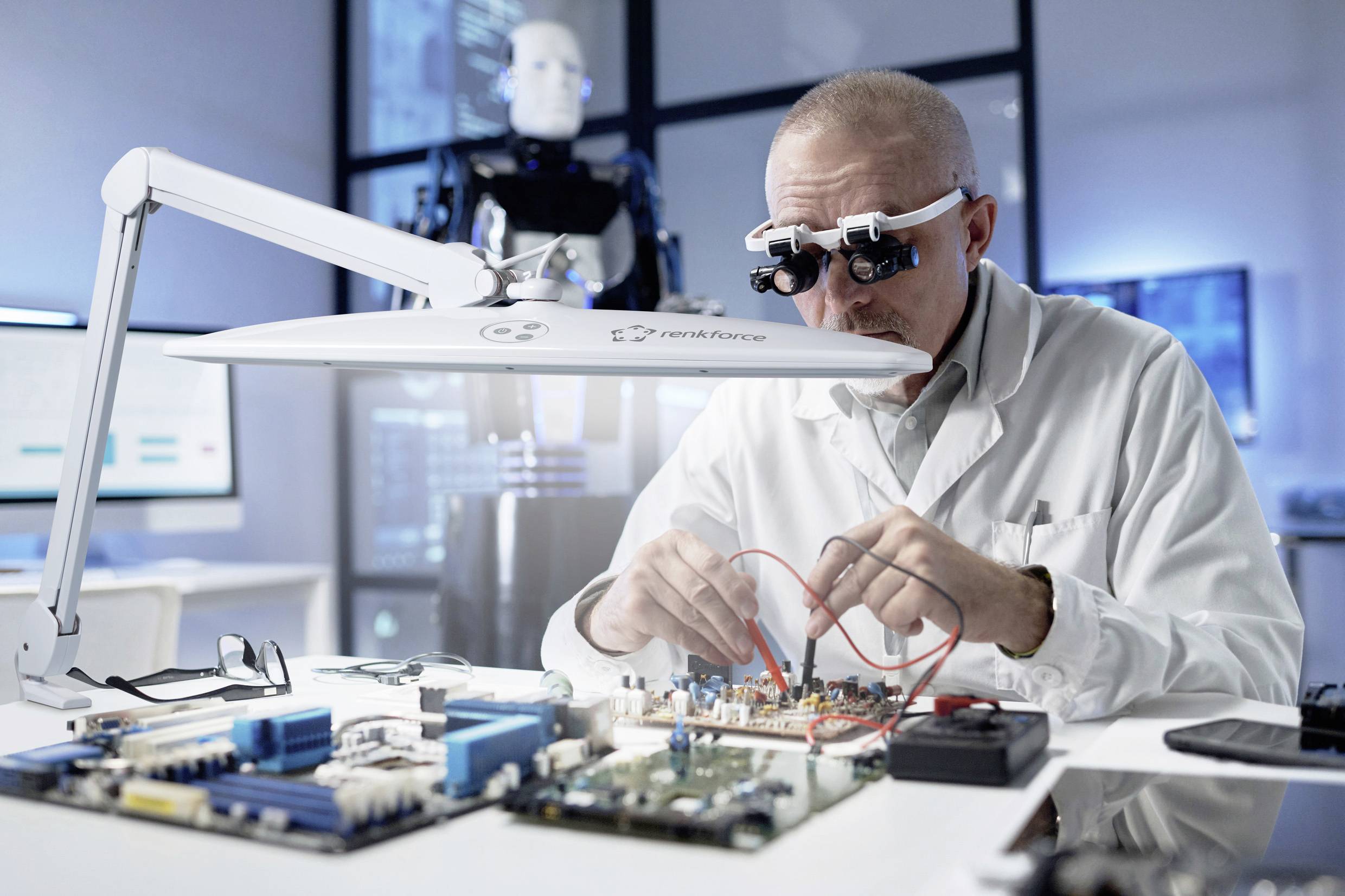 Inženýr zkoumá elektrickou desku v laboratoři. V pozadí je vidět robot. Prostředí působí futuristicky a technologicky.