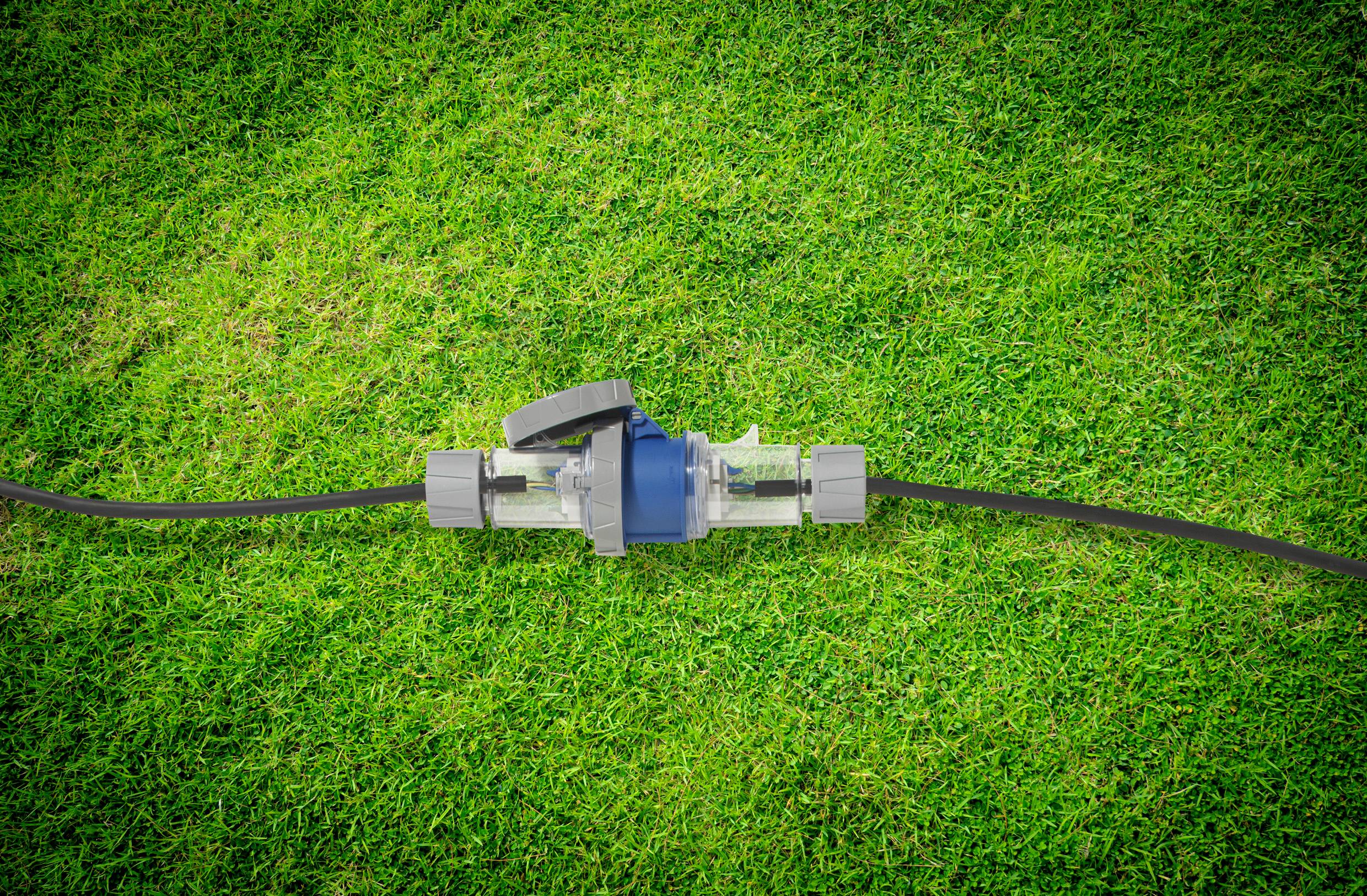 Zahradní hadice s ventilem leží na zelené trávě.