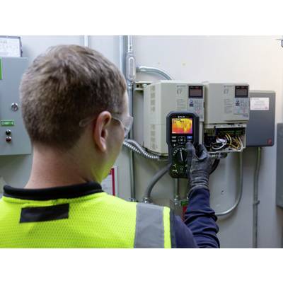 Technik používá infračervený teploměr ke kontrole elektrických řídicích zařízení v servisní místnosti.