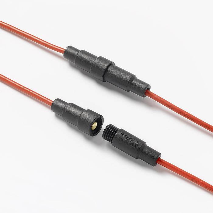 Dva červené elektrické kabely s černými konektory. Jsou propojeny a ukazují bezpečné elektrické spojení.