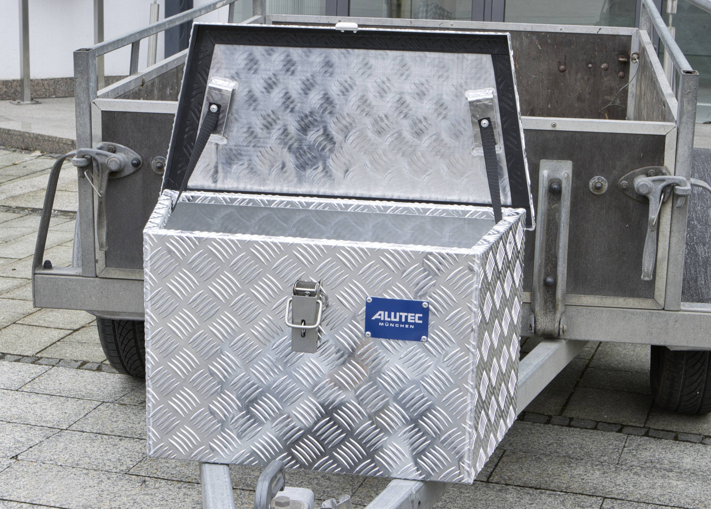 Otevřený hliníkový úložný box s vzorem, umístěný na přívěsu. Box zobrazuje logo 'Alutec'.