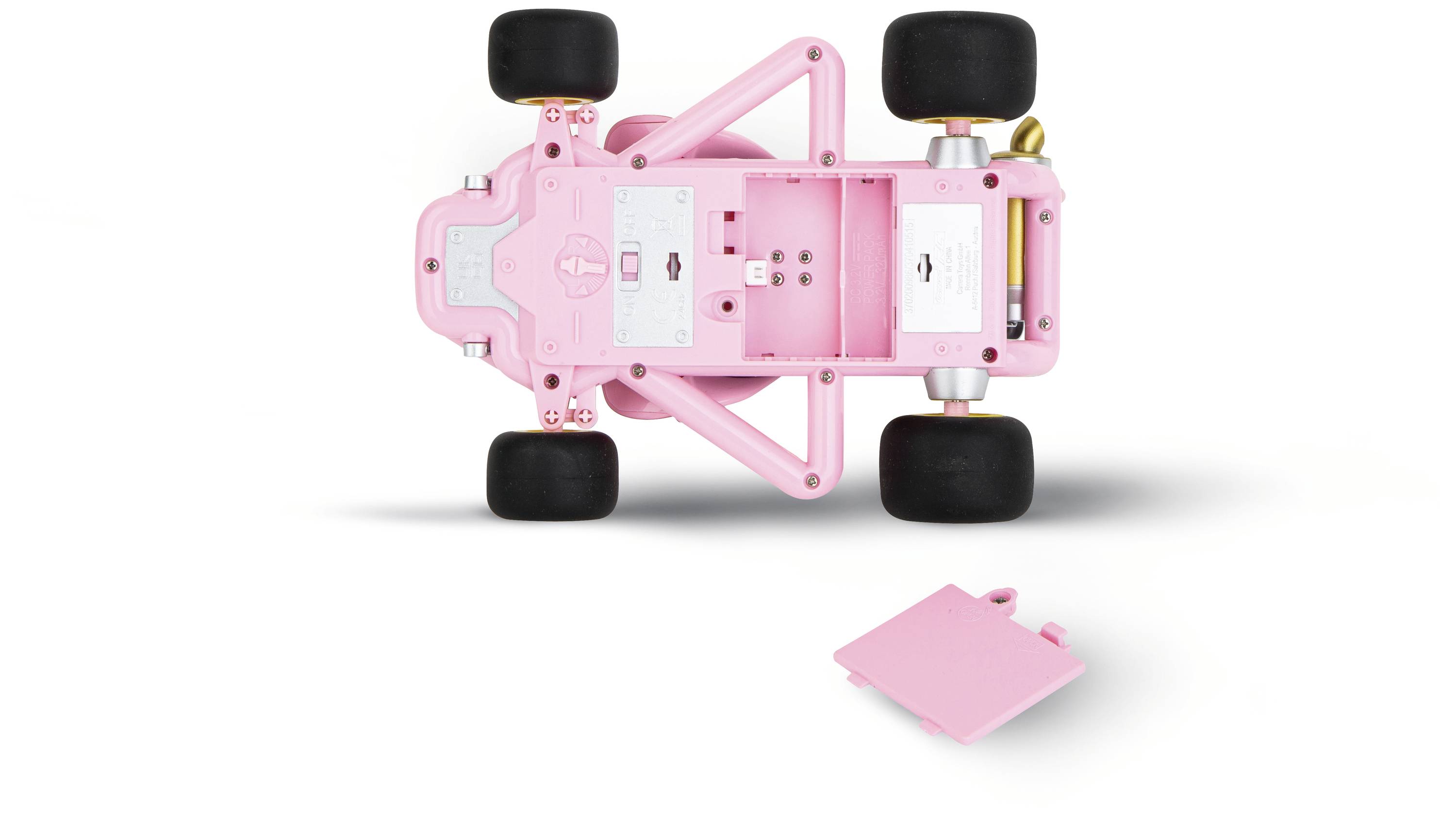 Růžové modelové auto pohledem zespodu, ukazující podvozek a čtyři kola. Vedle leží základní deska.