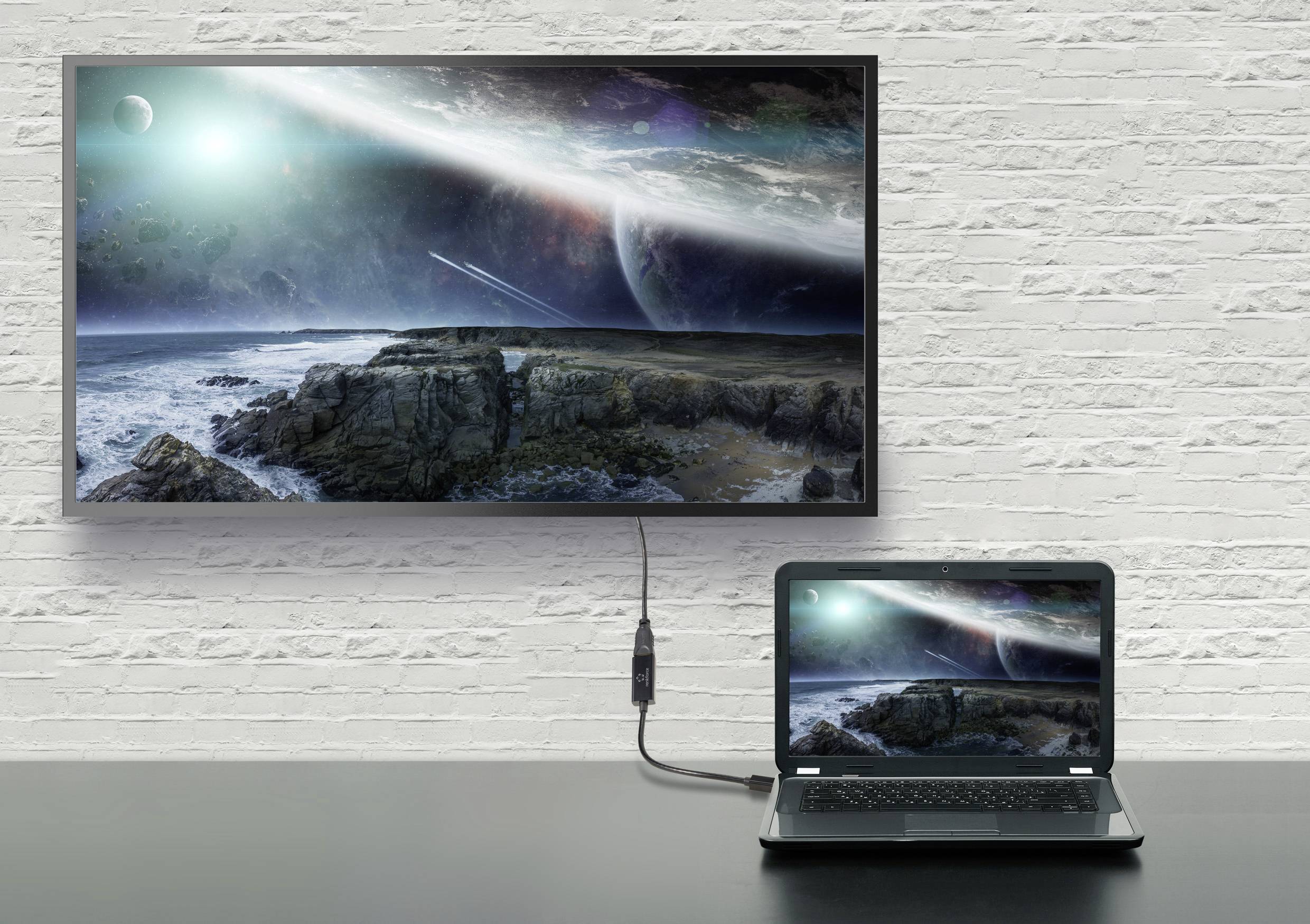 Notebook připojený k monitoru zobrazuje identickou vesmírnou scénu: skalnatý břeh pod oblohou planety. Sci-fi atmosféra, využití technologie.
