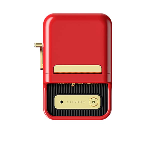 Červeno-zlaté přenosné zařízení s velkou klávesou, pravděpodobně tiskárna štítků. Retro design, kompaktní velikost, vestavěný tiskový otvor.