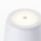 Bílá, kuželovitá lampa s měkkým světelným efektem na horní straně; moderní, minimalistický design.