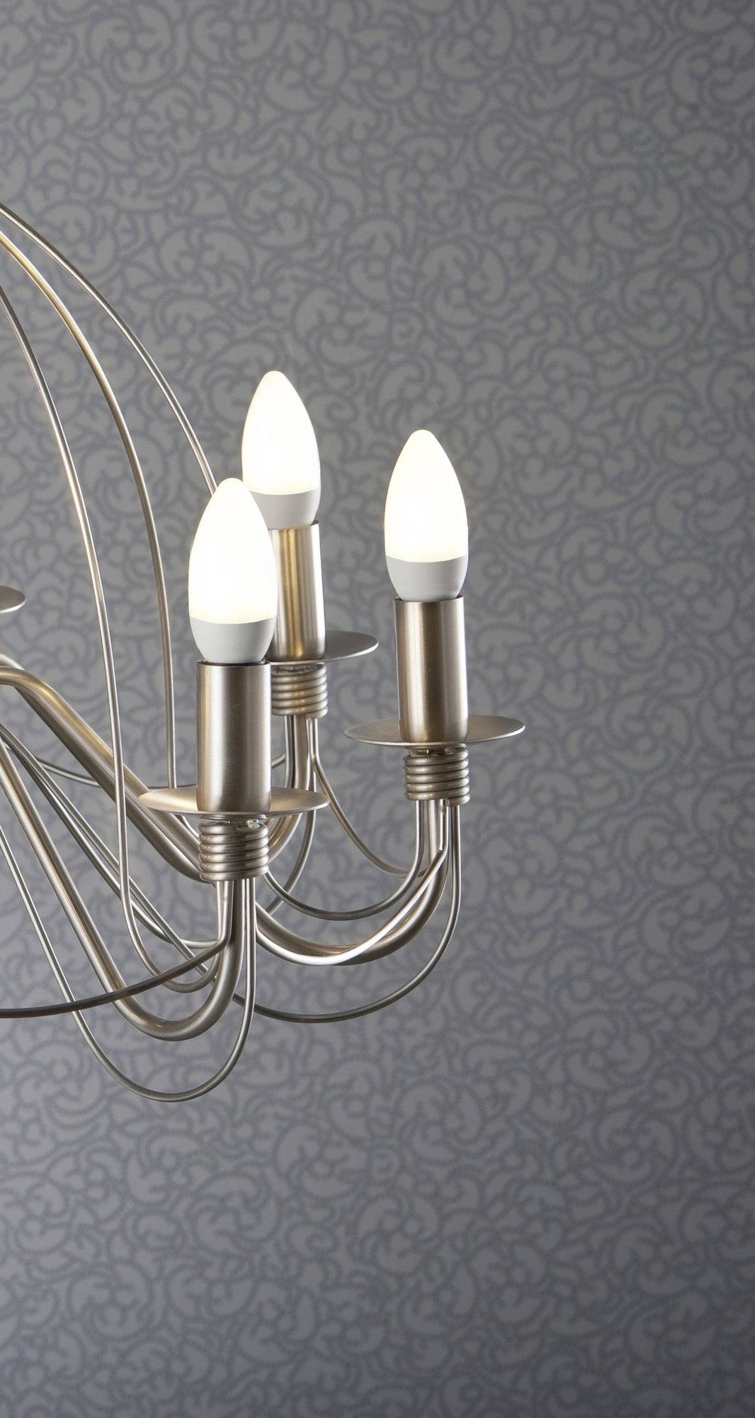 Tříramenný lustr s LED žárovkami v moderním designu před strukturovanou šedou tapetou.