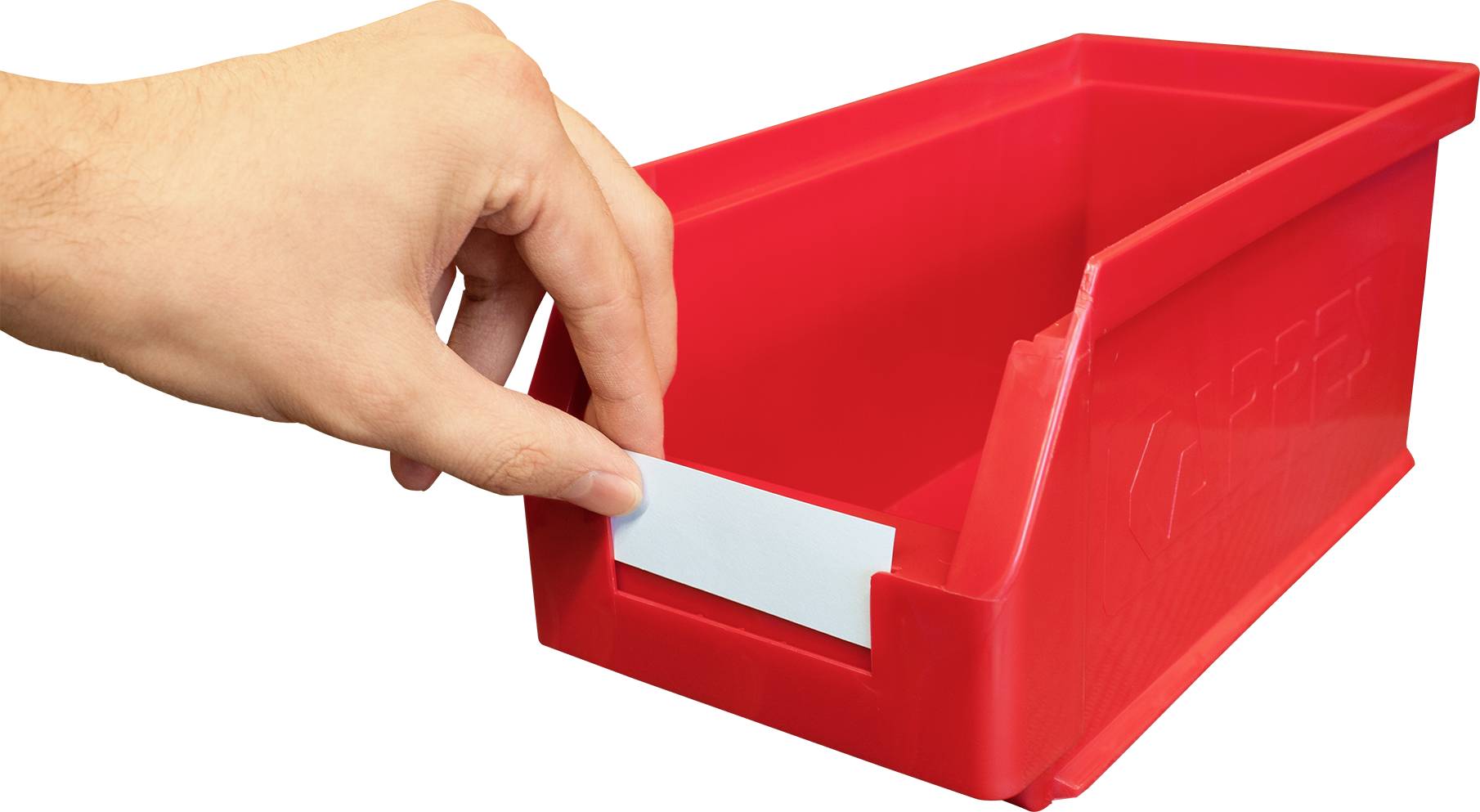 Ruka vkládá štítek do červené úložné krabice s otevřeným oddílem.