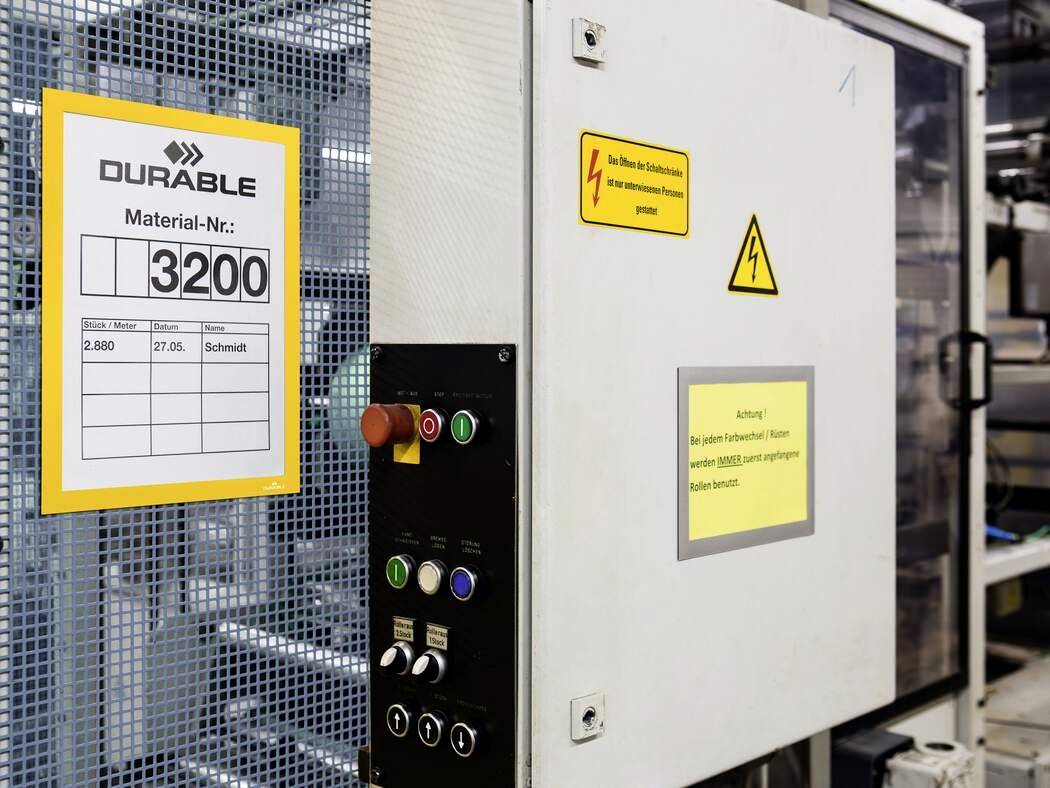 Strojní řízení s nouzovými tlačítky a zobrazovací panel s číslem materiálu '3200'. Důležité štítky: Varování před elektrickým napětím.