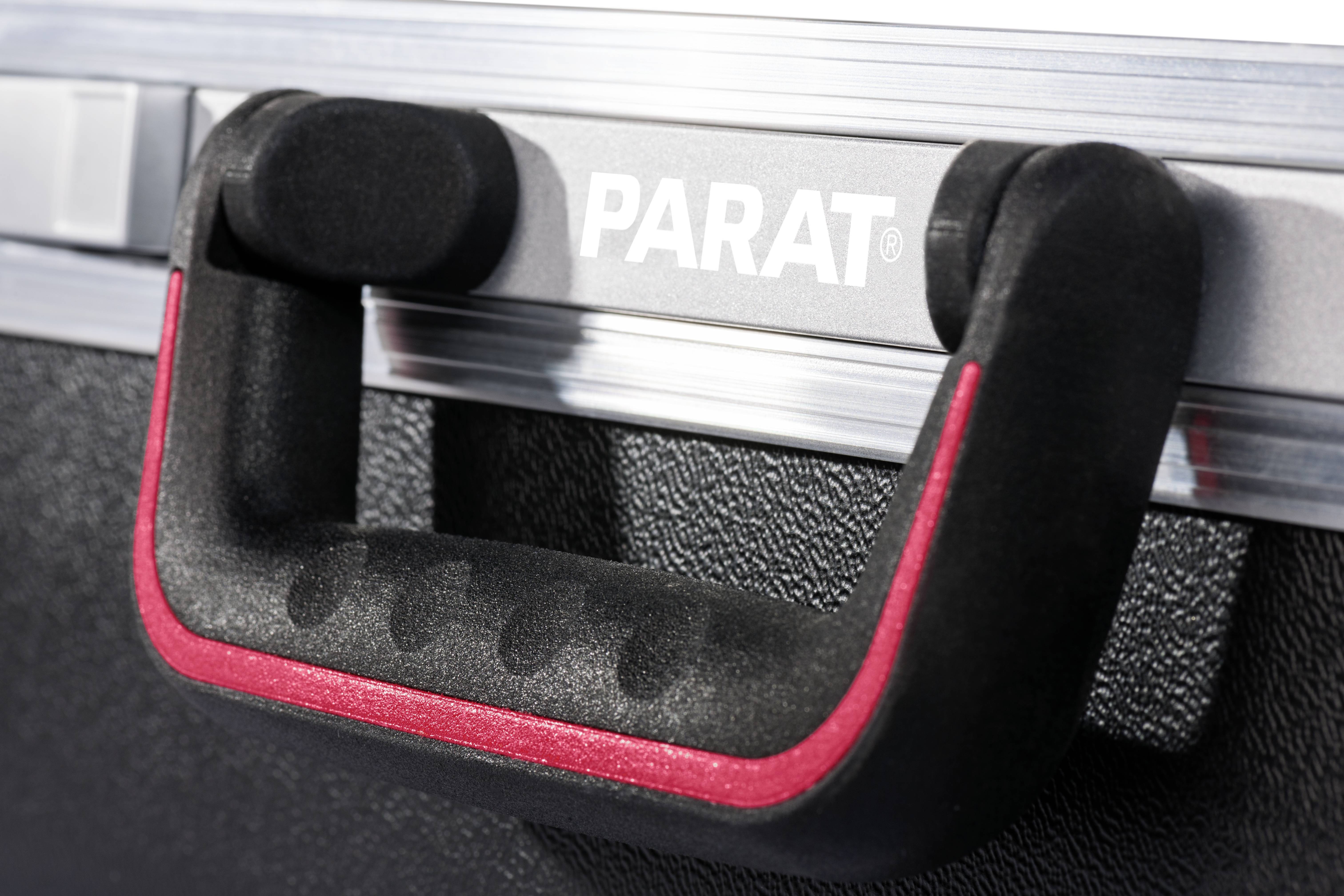 Detailní záběr černé rukojeti kufru s červeným pruhem na stříbrném kufru s nápisem 'PARAT'.