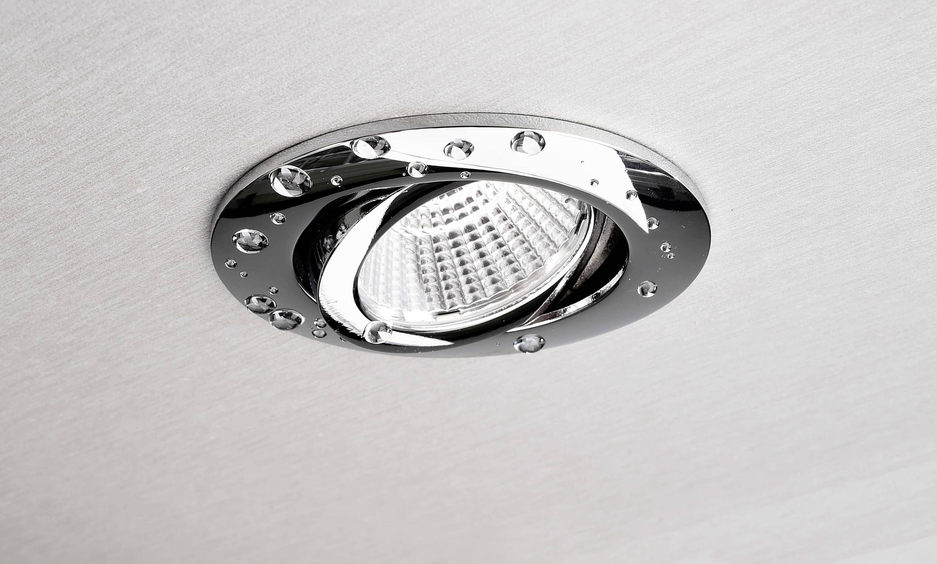 Moderní vestavěné LED svítidlo s chromovaným okrajem, zabudované do světlého stropu, osvětluje prostor funkčním způsobem.