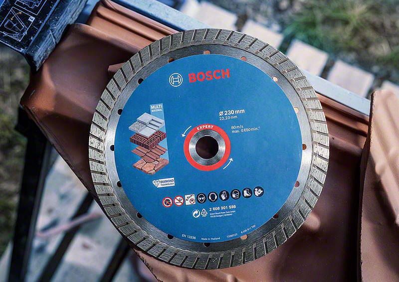 Bosch řezný kotouč o průměru 230 mm, vhodný pro cihly a beton. Leží na cihlách a je připraven k použití.