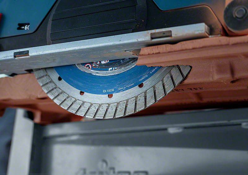 Kotoučová pila s modrým a stříbrným pilovým kotoučem, částečně zasunutým do krytu. Vypadá, že je připravena k řezání.