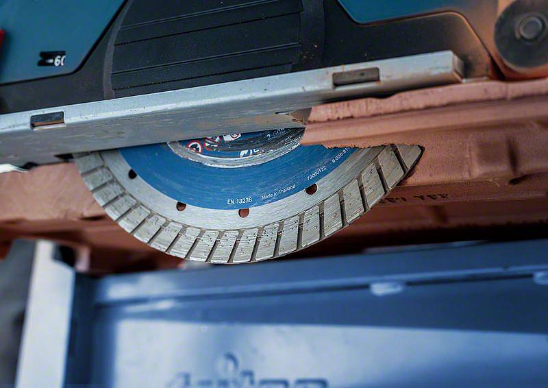 Detailní záběr kotoučové pily při řezání materiálu. Kovové zuby pily jsou zřetelně viditelné.