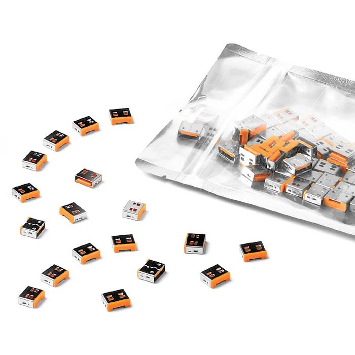 Hromada malých oranžových a černých USB dongles na bílém pozadí, některé volně rozložené a některé v průhledném plastovém obalu.