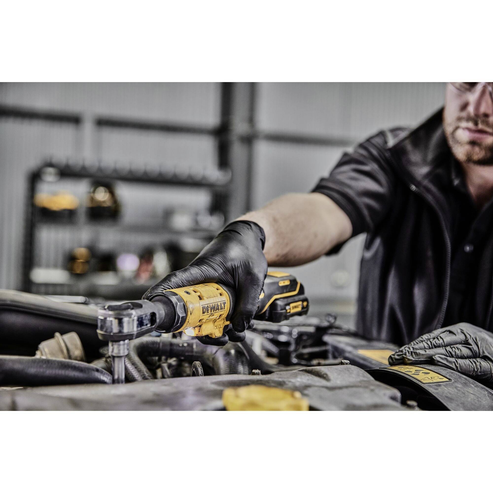 Mechanik používá momentový klíč DeWalt při práci na motoru. V pozadí jsou viditelné další nástroje.