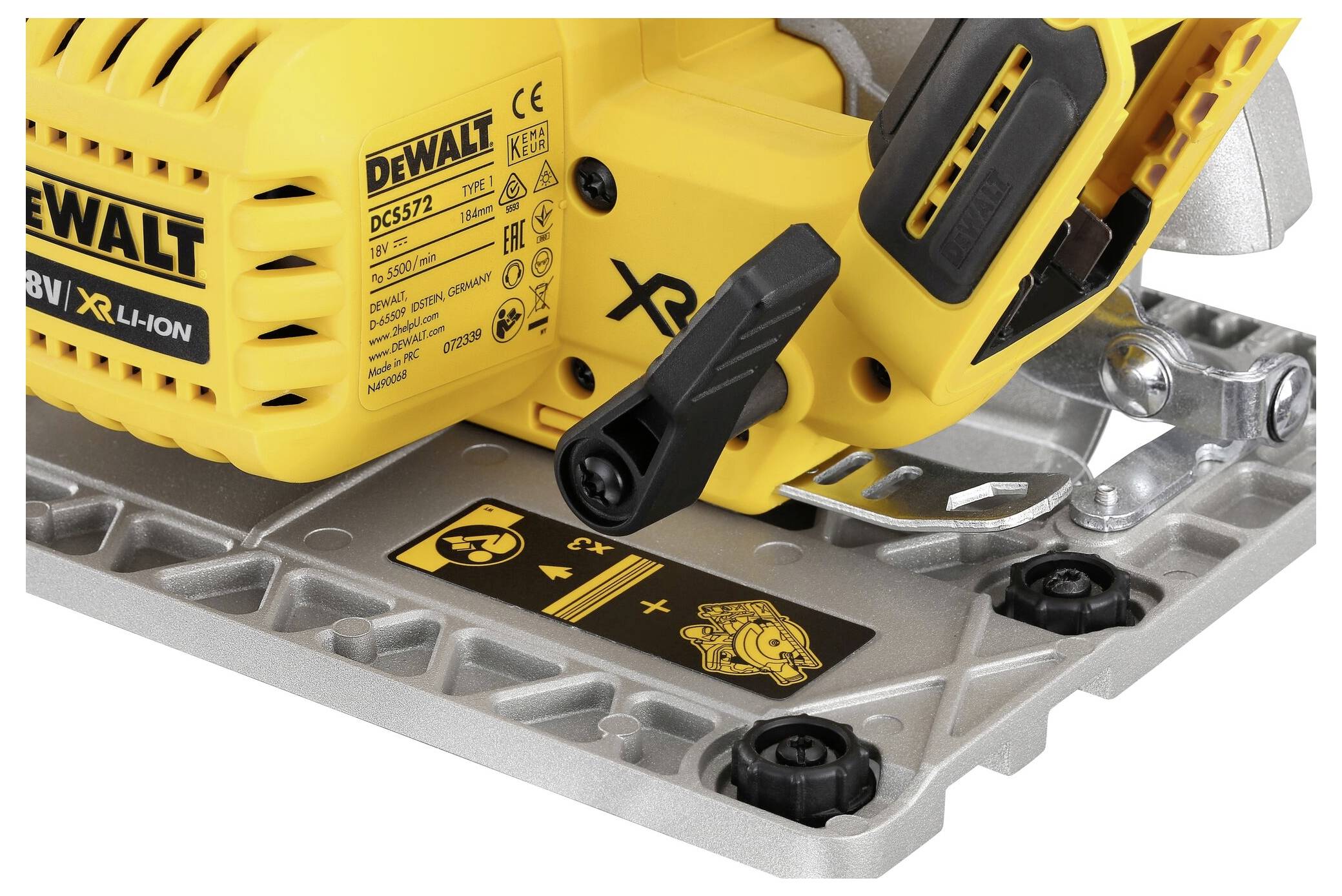 Detailní pohled na žlutou aku ruční kotoučovou pilu DeWalt s ovládací pákou a výstražnými symboly. Viditelné šroubové upevnění a kovová deska.