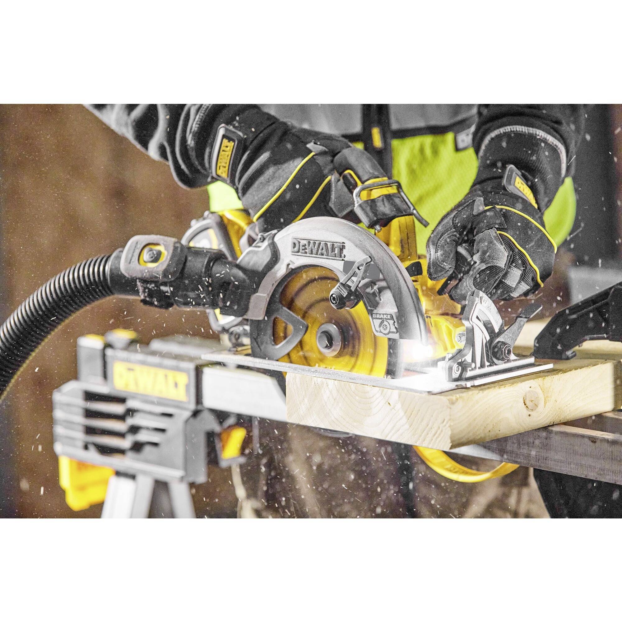 Osoba řeže elektrickou ruční kotoučovou pilou DeWalt dřevěný kus, přičemž třísky létají do okolí.