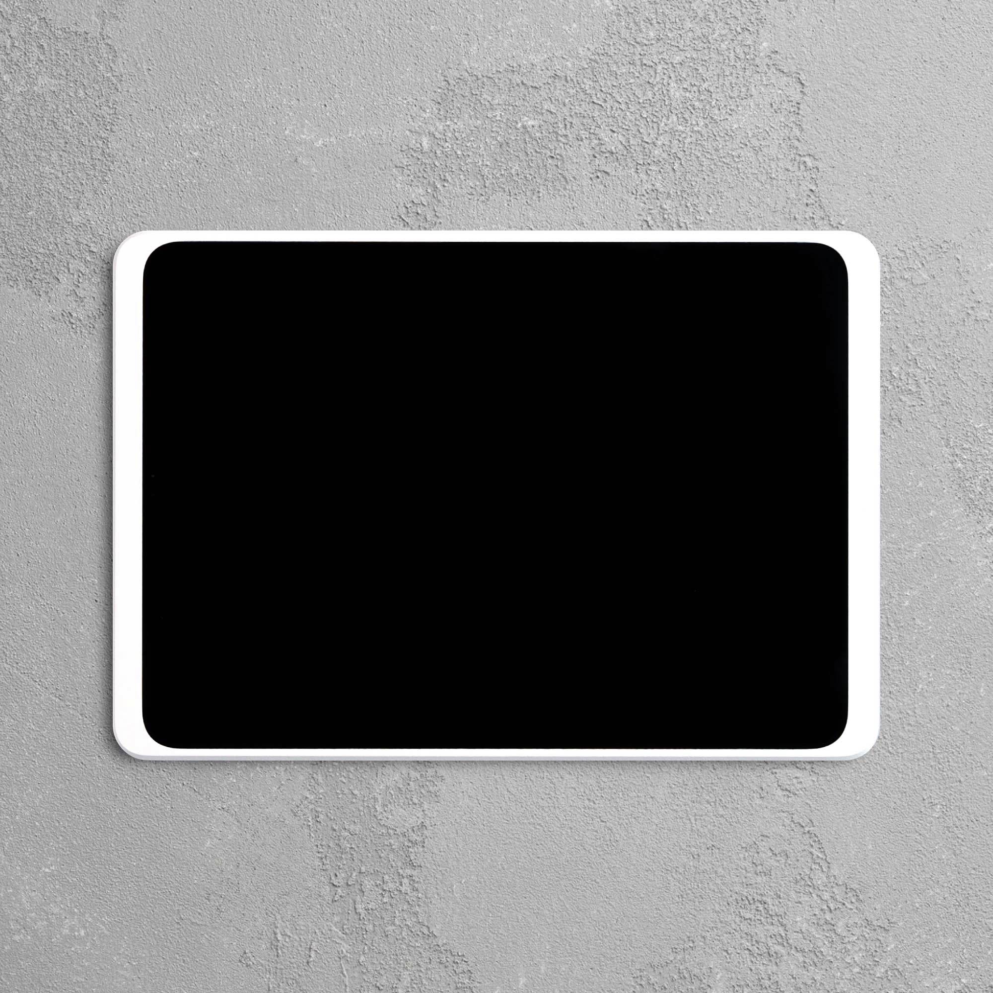 Černý tablet s bílým rámečkem leží na šedém strukturovaném povrchu.