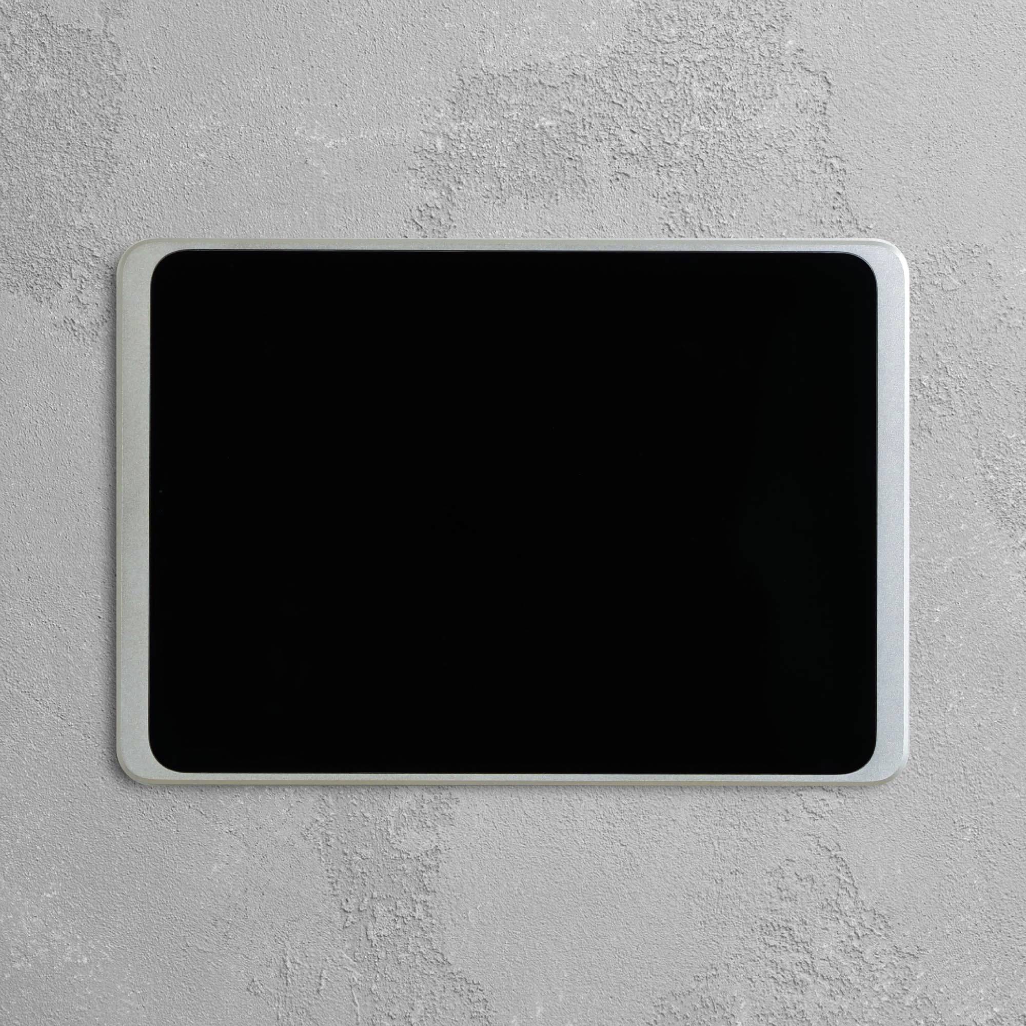 Tablet s černou obrazovkou leží na šedém povrchu.