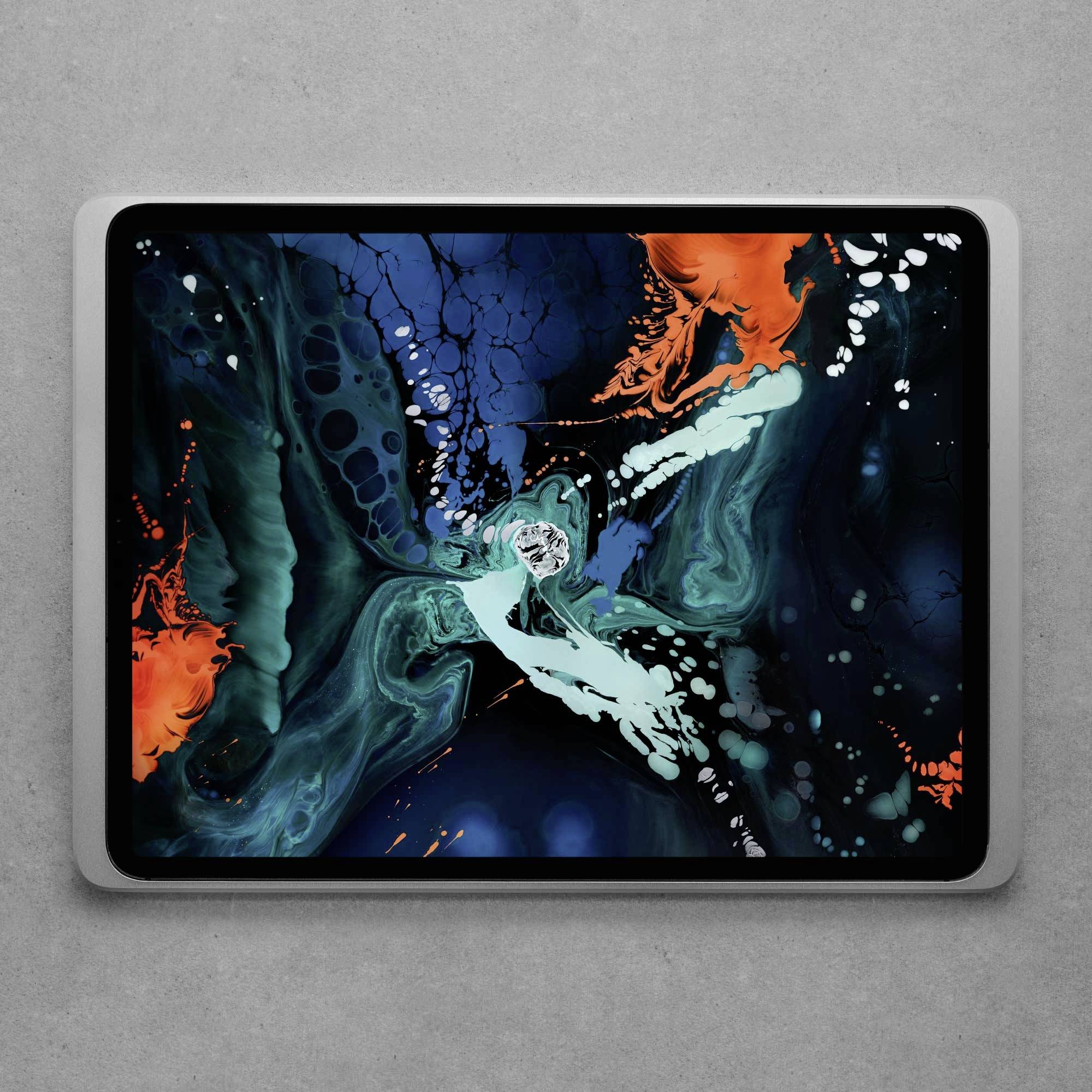 Abstraktní obraz na tabletu s modrými, zelenými a oranžovými víry, které do sebe prolínají. Umělecké dílo na šedém pozadí.