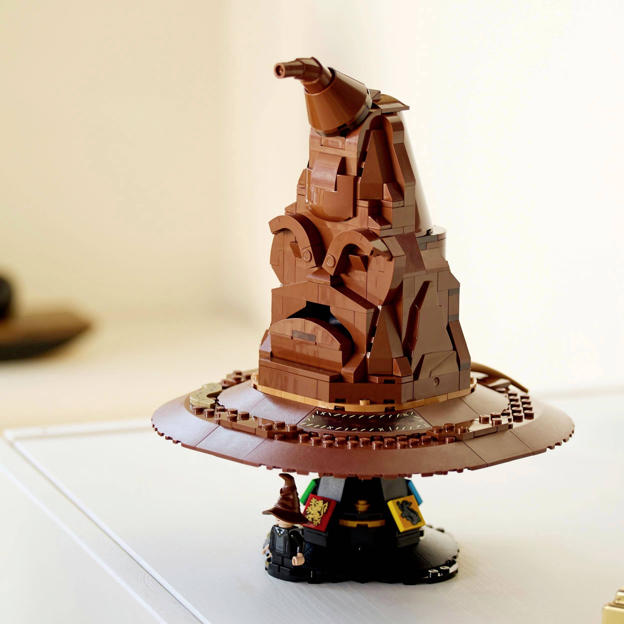 Lego model čarodějnického klobouku s obličejem, umístěný na kulatém podstavci. Klobouk má výrazný špičatý tvar.