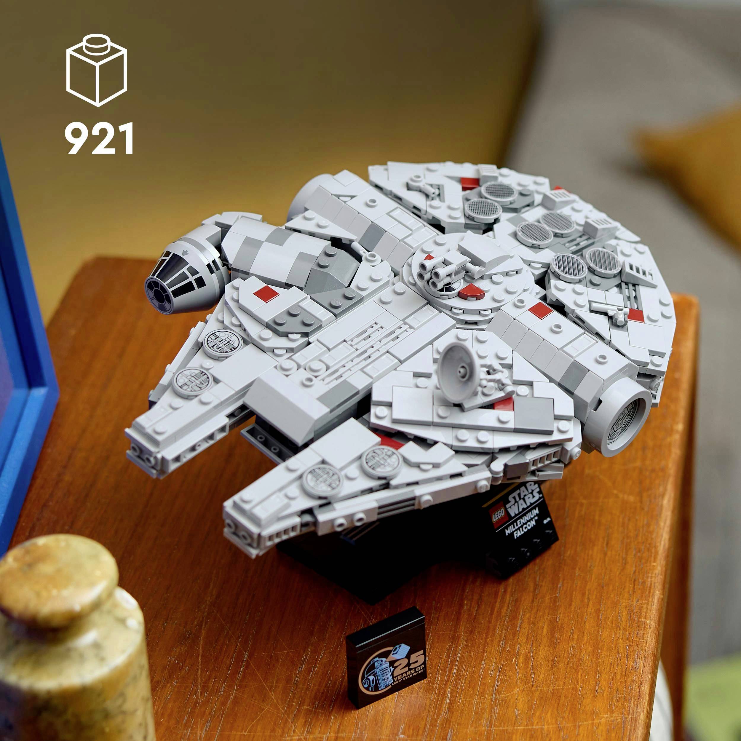 Model LEGO vesmírné lodi na stole. Zobrazuje detaily a ozdoby lodě, včetně podstavce a štítků.