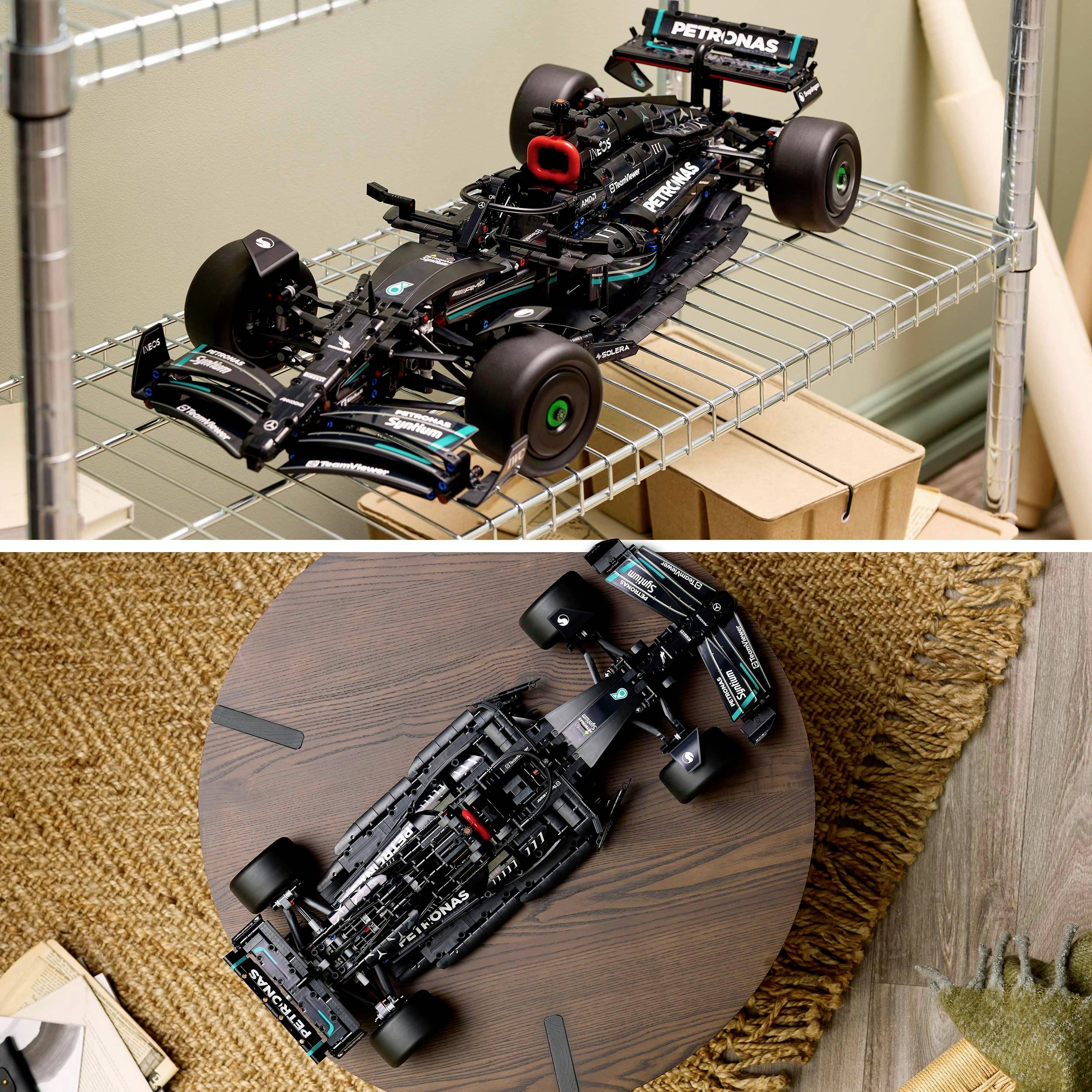 Černý model formule 1 s logem PETRONAS umístěný na kovovém regálu a dřevěném stole.