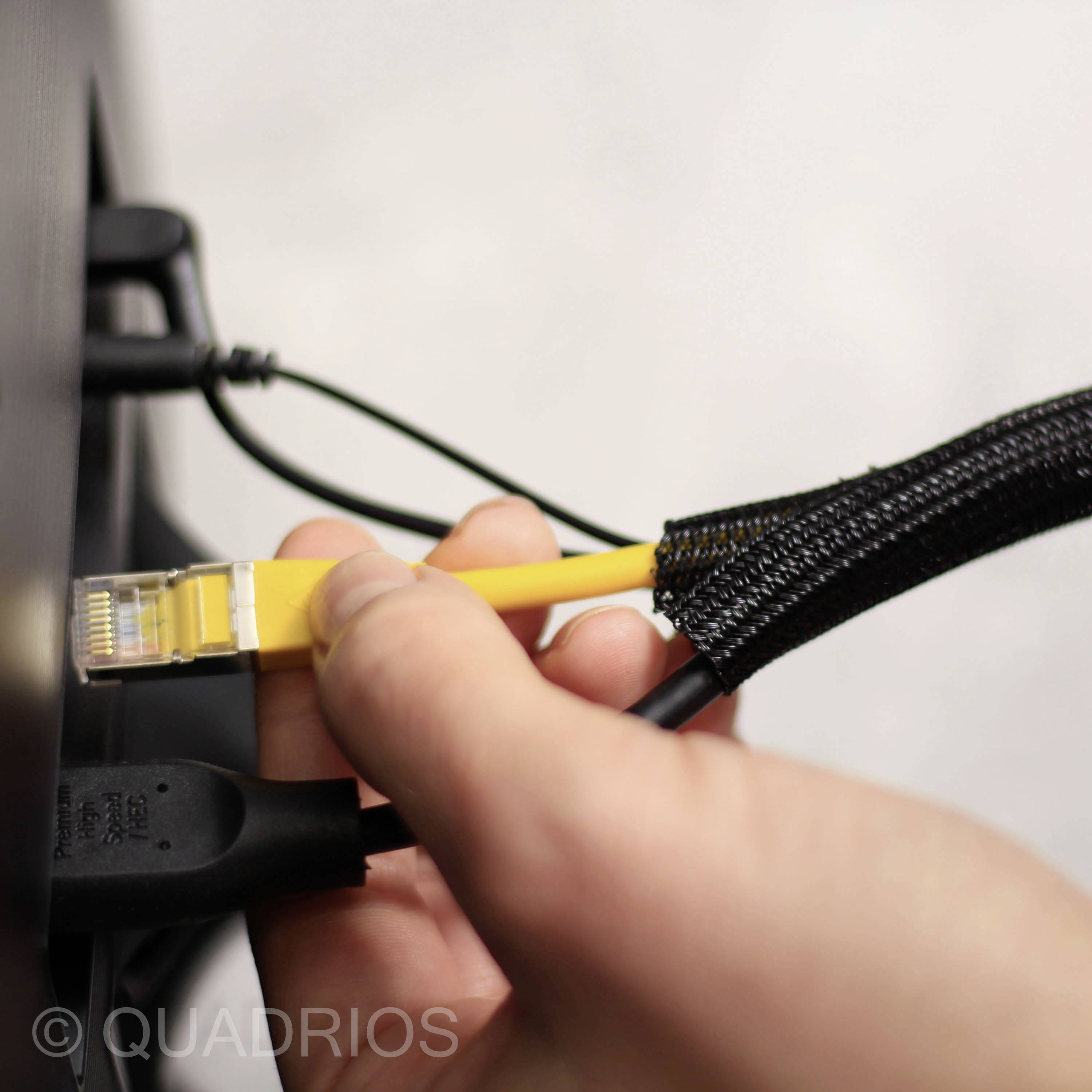Detail záběru ruky, která zapojuje žlutý ethernetový kabel do černého síťového portu. Jsou viditelné prvky správy kabeláže.