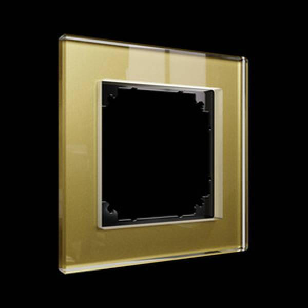 Rámeček vypínače ve zlaté barvě, skleněný vzhled, obdélníkový, na černém pozadí. Elegantní design pro moderní interiéry.