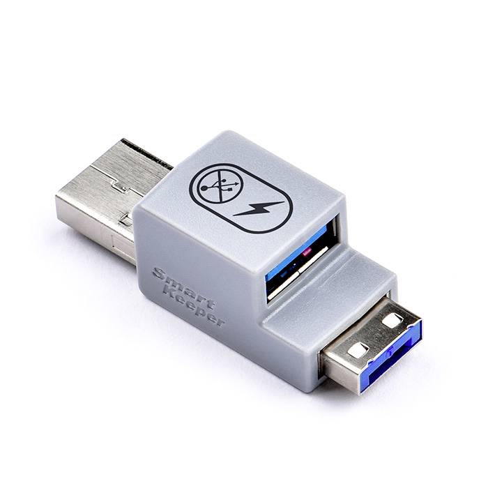 USB zařízení s nápisem 'Smart Keeper' blokuje přístup k USB portu. Obsahuje symboly bezpečnosti a ochrany.