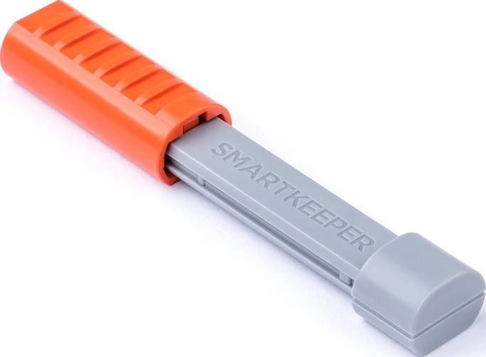 Oranžovo-šedé plastové zařízení s nápisem 'SMARTKEEPER', pravděpodobně bezpečnostní nebo uzamykací mechanismus.