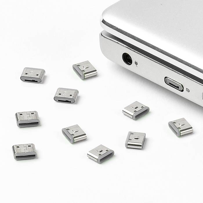 Laptop s několika USB adaptéry na bílém povrchu, zobrazující všestranné možnosti připojení.