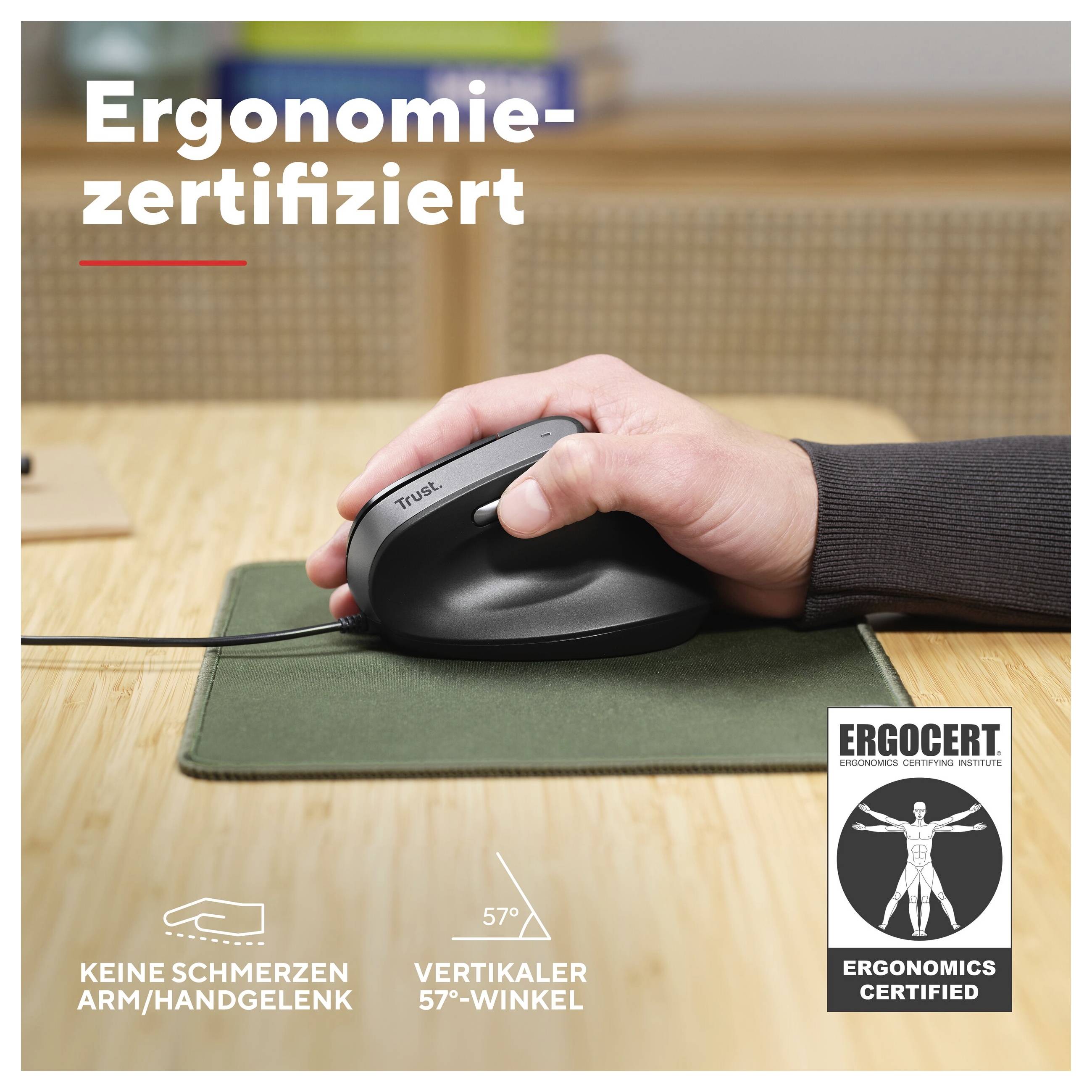 Jedna osoba používá vertikální myš značky Trust na zelené podložce pod myš. Text: 'Ergonomicky certifikováno', 'Žádné bolesti paže/zápěstí', 'Vertikální úhel 57°'.