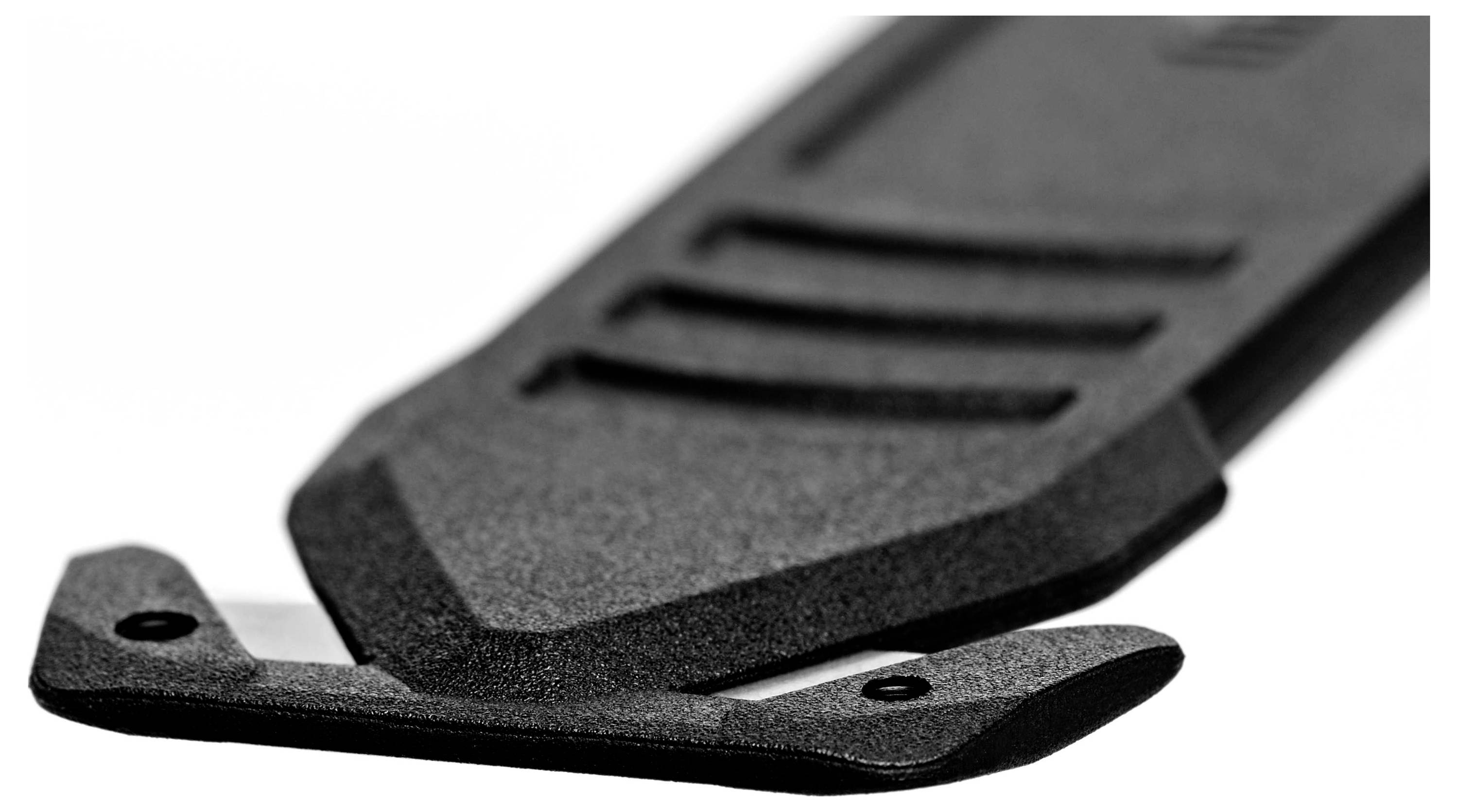 Černý koberový nůž s vysunutou čepelí, zachycující detail designu a textury v detailním záběru.