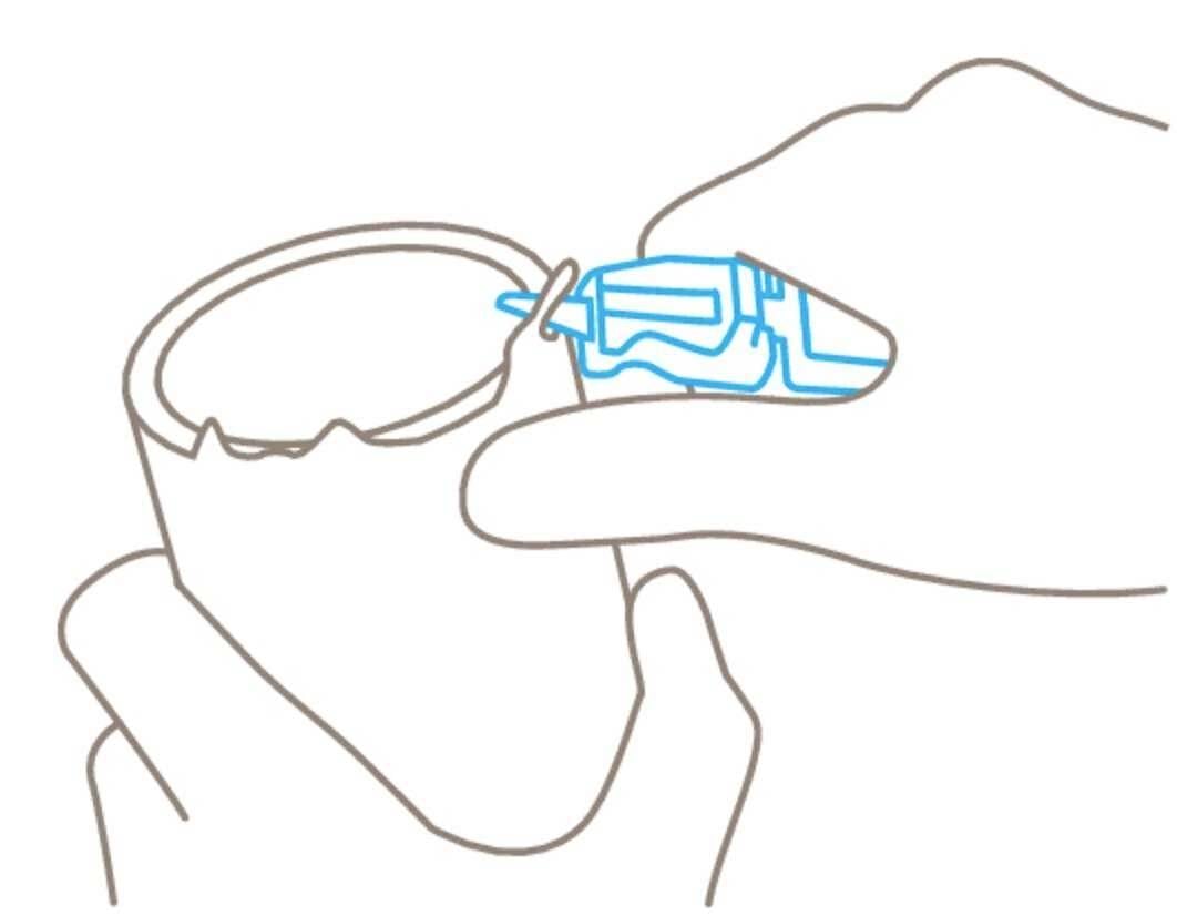 Jedna ruka drží šálek, zatímco druhá ruka nanáší lepidlo na okraj šálku.