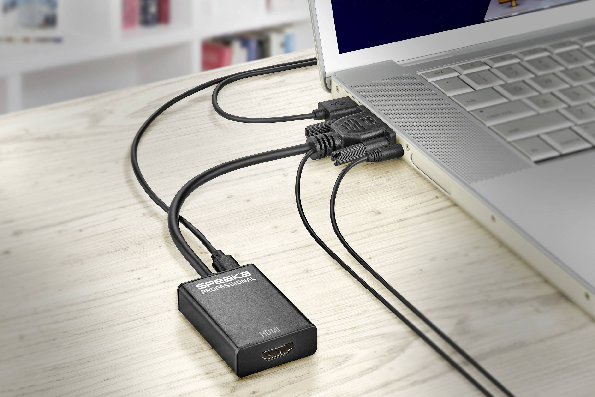 Laptop na stole, připojený několika kabely, včetně HDMI kabelu, který je připojen k HDMI adaptéru.