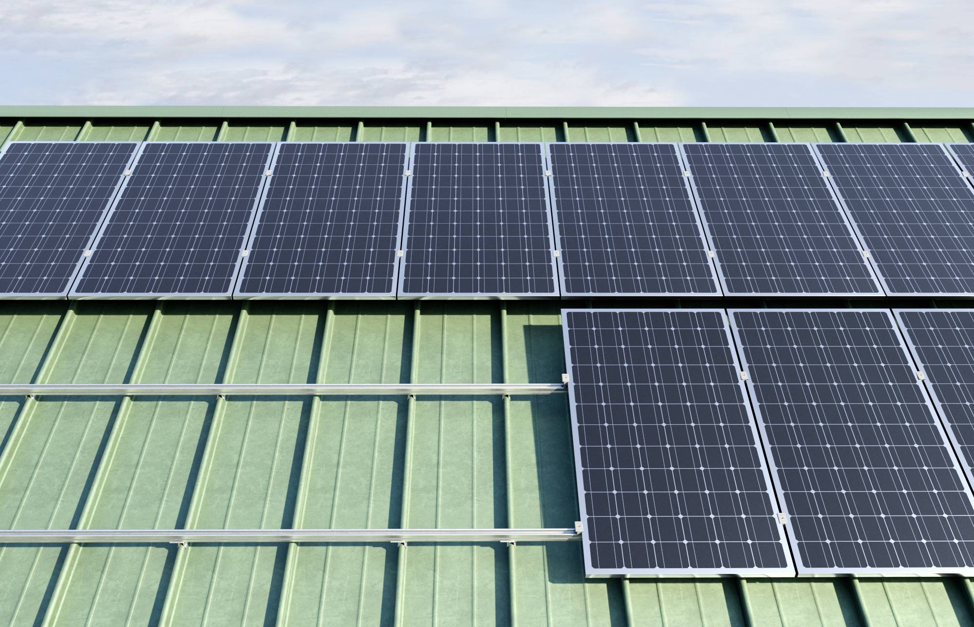 Solární panely na zelené kovové střeše, které přeměňují sluneční energii na elektřinu. Na pozadí čistá obloha.