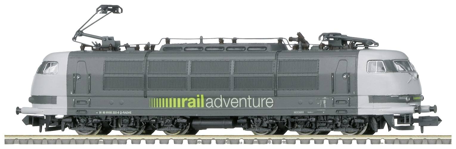 Šedá elektrická lokomotiva s nápisem 'rail adventure' na boku, stojící na kolejích. Má aerodynamický tvar.