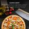 Pizza na dřevěné desce, velké ostří nože vedle. Text nahoře: 'Gumová rukojeť'. Ingredience: olivový olej, rajčata, pepřová zrna.
