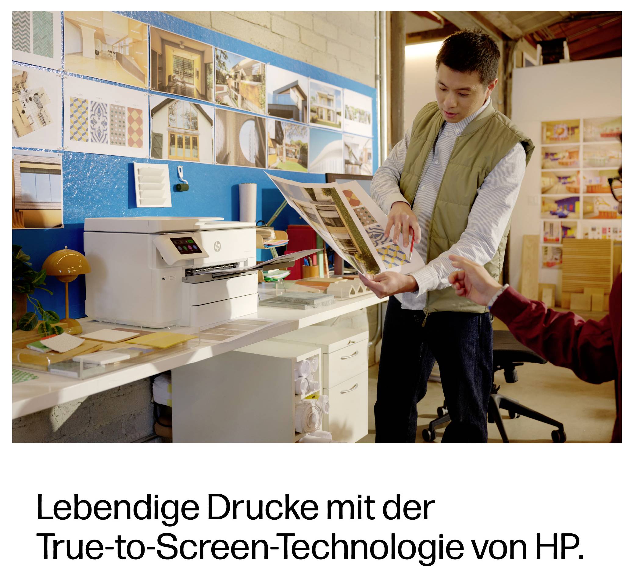 Muž zkoumající tištěný podklad v designovém studiu; německý reklamní text zní "Životná tiskovina s technologií True-to-Screen od HP."